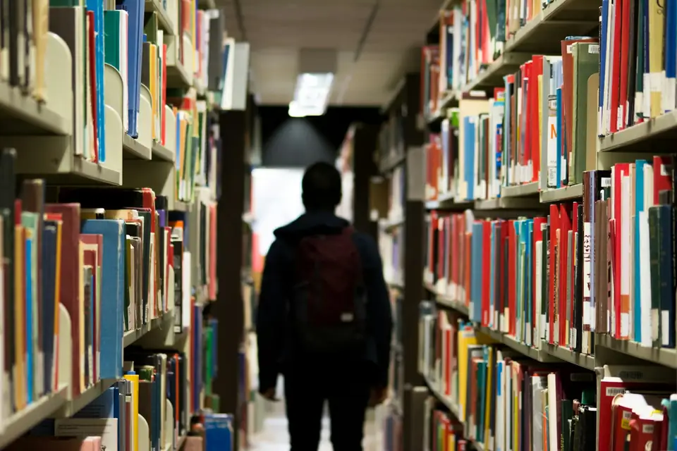 Un élève entre les rayonnages d'une bibliothèque