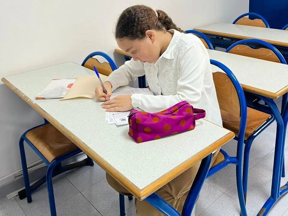 Élève écrivant dans son cahier pendant un cours de français au centre FLC à Tanger